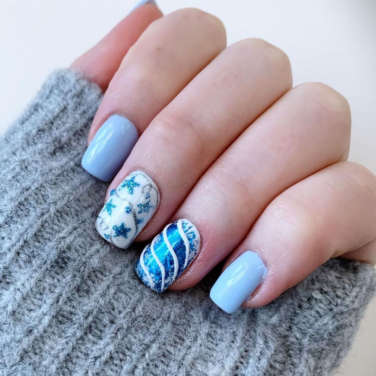 26. Glittery Blue and Silver Snowflakes on Short Nails