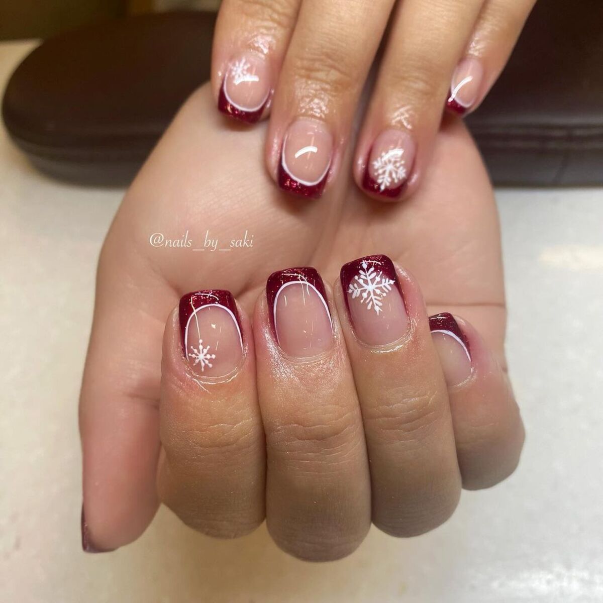 12. Crimson French Tips with Delicate Snowflakes