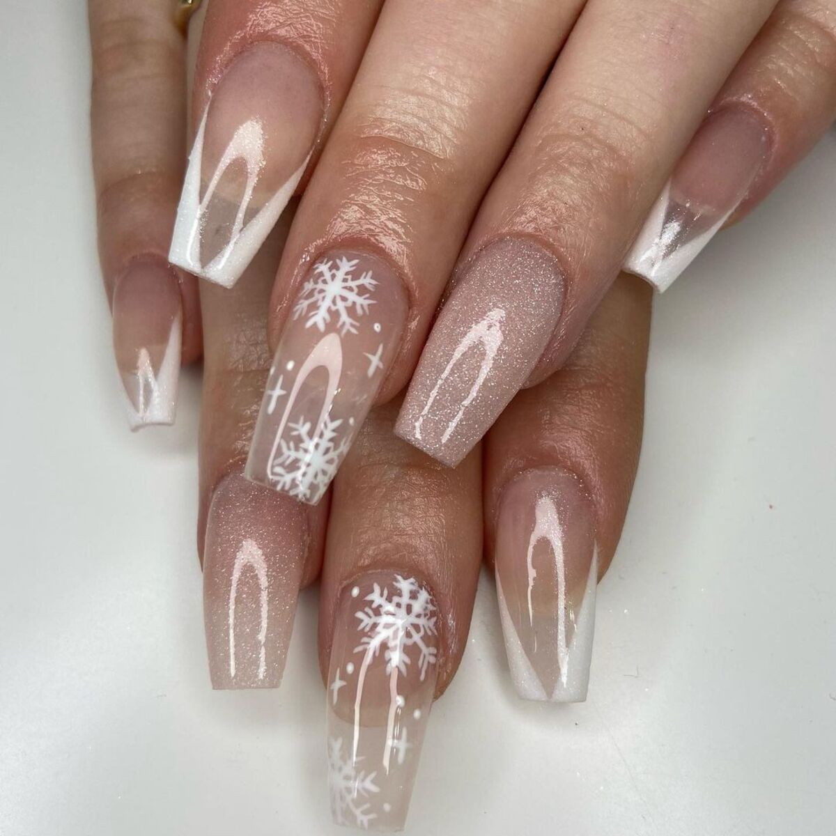 5. Glittery White Snowflakes on Blush Nails