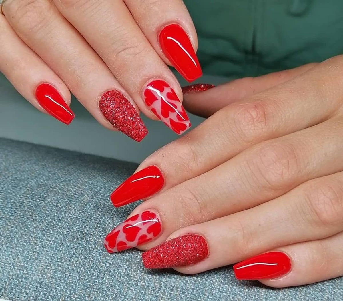 25. Bold Red Nails with Glitter and Heart Patterns