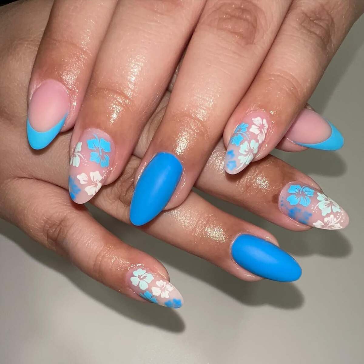 5. Bold Blue Floral Patterns on Almond Nails